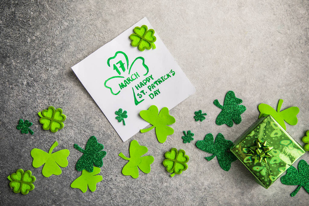 Decoratieve klaverblad, groene geschenkdoos, munten op stenen achtergrond, platte lay. St. Patrick 's Day feest. Kaart Gelukkige St. Patrick 's Day - Foto, afbeelding