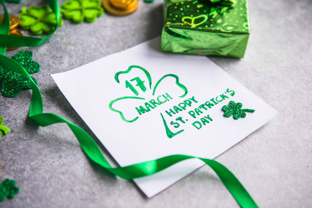 Feuilles de trèfle décoratives, boîte cadeau verte, pièces sur fond de pierre, pose plate. Fête de la Saint-Patrick. Carte Joyeuse Saint-Patrick - Photo, image