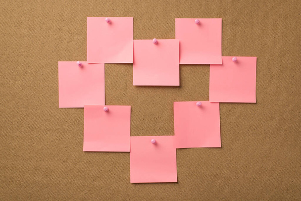 Hyvää ystävänpäiväkonseptia. Kuva pastelli vaaleanpunainen tarroja tehdä muoto sydämen kiinnitetty nastat puinen tausta - Valokuva, kuva
