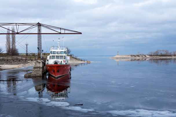 Cherkasy, Ουκρανία, Ιανουάριος 2021. Παλιό εγκαταλελειμμένο κόκκινο πλοίο στον παγωμένο ποταμό Δνείπερου.. - Φωτογραφία, εικόνα