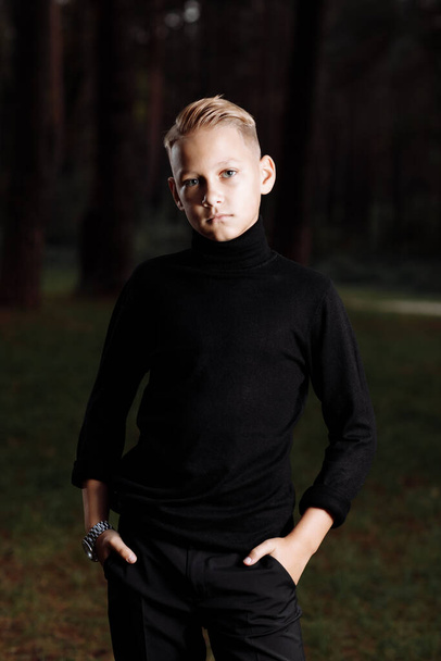 Стильний привабливий молодий хлопець з модною зачіскою в модному чорному вбранні насолоджується відпочинком на відкритому повітрі в парку
 - Фото, зображення