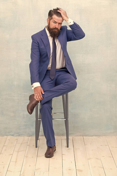 Confident and stylish. Classy hipster sit on chair. Bearded man touch hipster hair. Trendy hipster style. Fashion barbershop. Business dress code and formalwear. Hipster lifestyle - 写真・画像
