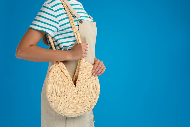 Young woman with stylish straw bag on light blue background, closeup. Space for text - Fotografie, Obrázek