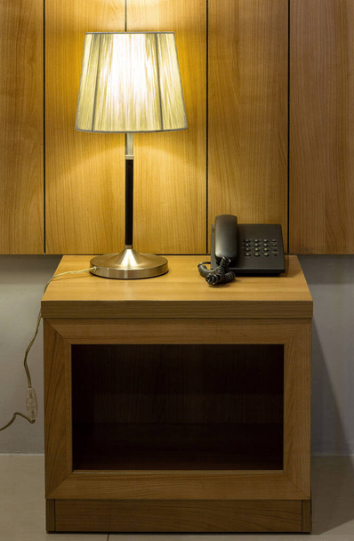 Asztali lámpa és telefon az asztalon a hálószobában - Fotó, kép