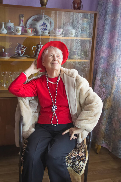 Модная старшая женщина носит ожерелье на домашнем фоне - Фото, изображение