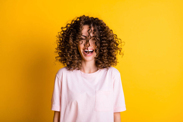 Photo portrait of laughing happy girl with stylish curly hairdo wearing t-shirt isolated on vibrant yellow color background - Foto, immagini