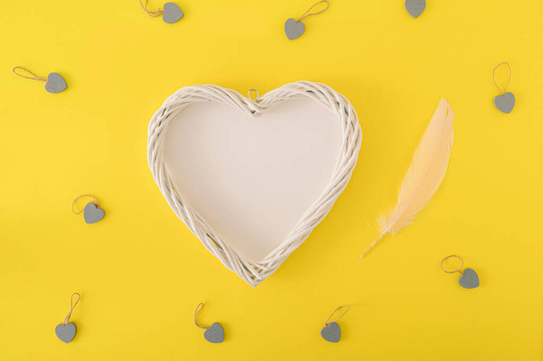 Spazio copia creativo realizzato con forma di cuore.Piuma e piccoli cuori su sfondo giallo.Lay piatto, Love Concept. - Foto, immagini