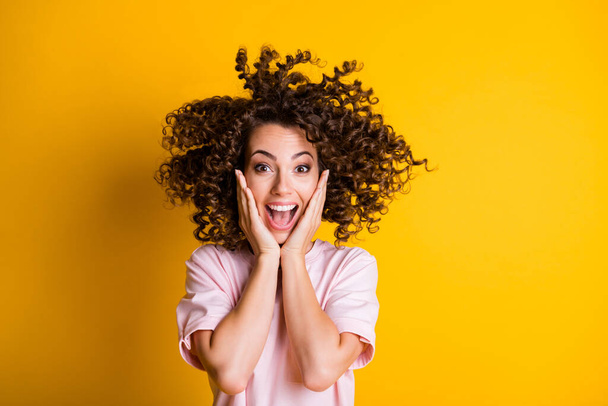 Photo portrait of happy shocked curly girl touching cheeks with both hands yelling isolated on vivid yellow color background - Valokuva, kuva