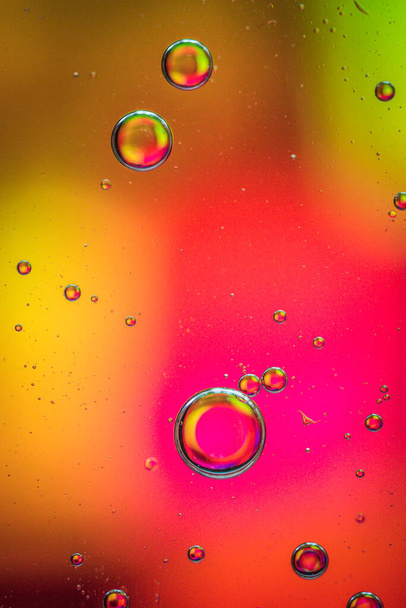 gotas de aceite sobre una superficie de agua fondo abstracto con colores amarillos y rojos - Foto, Imagen