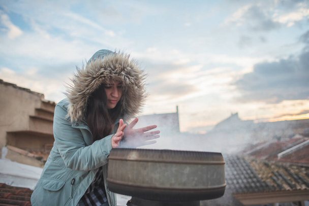 Дівчина захищена на даху свого будинку, зігріваючись димом і теплом від каміна
 - Фото, зображення