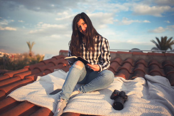 Donna in un momento di relax leggendo sul tetto della sua casa - Foto, immagini