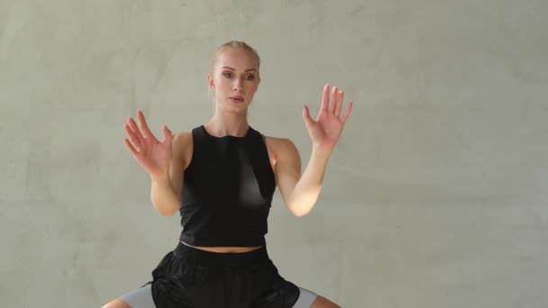 Sportlerin mit blonden Haaren trainiert und wärmt sich im Zimmer auf - Filmmaterial, Video