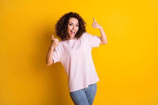 Photo portrait of happy girl raising two thumbs up isolated on vivid yellow colored background - Photo, image