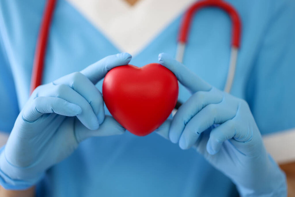 Dokter in handschoenen houdt een rood hart close-up - Foto, afbeelding