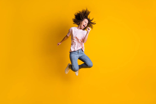 Photo portrait full body view of girl screaming into imaginary microphone jumping up isolated on vivid yellow colored background - Foto, Bild