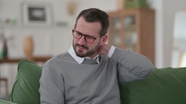 Hombre de mediana edad con dolor de cuello en el sofá  - Metraje, vídeo