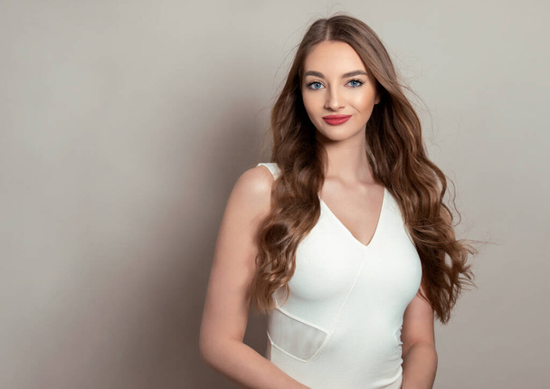 Beautiful young woman with long shiny and healthy hair posing in dress on grey background - Fotoğraf, Görsel