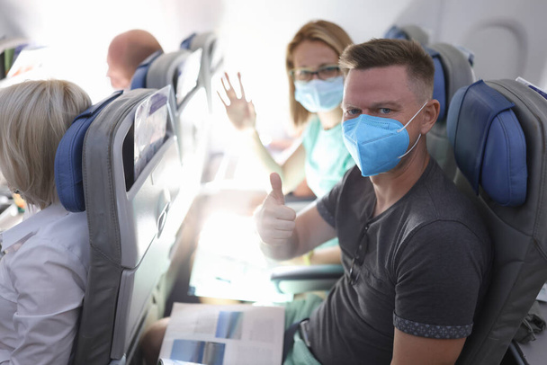 Άντρας και γυναίκα με ιατρικές προστατευτικές μάσκες στο αεροπλάνο - Φωτογραφία, εικόνα
