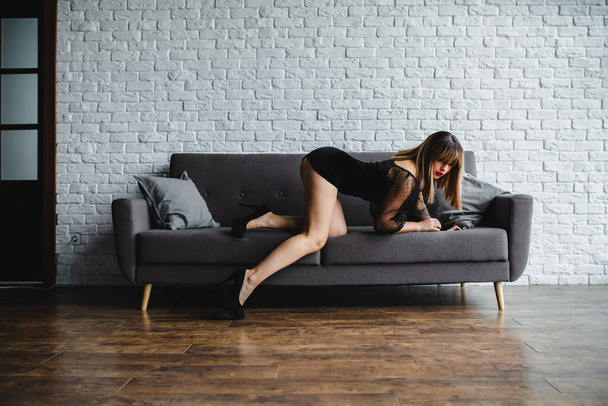 Young sexy blonde with naked legs in high heel shoes posing near the sofa - Fotografie, Obrázek
