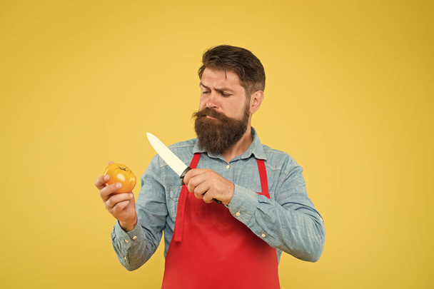 Sweet and soft. cooking healthy and fresh food. Handsome male chef is working. mature cook cut vegetable. guy in uniform on kitchen. vitamin dieting. bearded man in red apron with yellow tomato - Photo, image