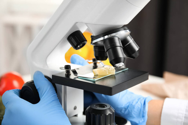 Scientist inspecting slice of lemon with microscope in laboratory, closeup. Poison detection - Valokuva, kuva
