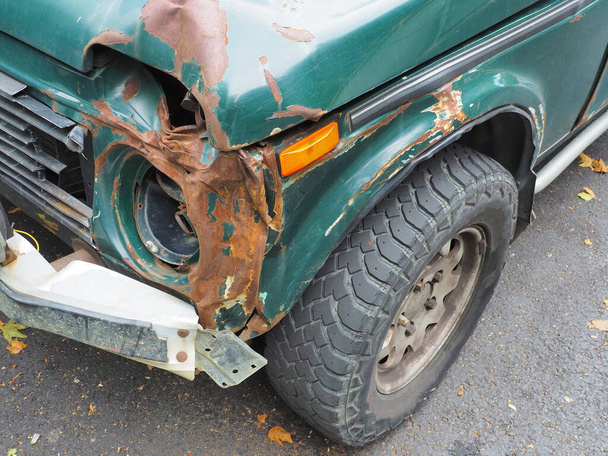 Фрагмент зеленой машины со сломанной ржавой передней и без фары - Фото, изображение