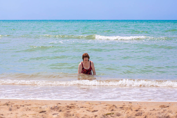 cheerful elderly woman aged 65 plus, bathes in the blue sea, laughs and enjoys a summer day, the end of quarantine and self-isolation - Фото, изображение