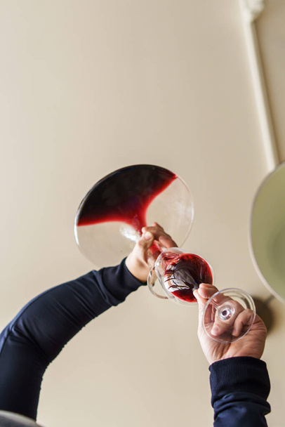 Blisko na rękach nieznanego białego człowieka wylewanie czerwonego wina z butelki w karafce w domu w dzień - niski kąt widzenia przestrzeń kopiowania - Zdjęcie, obraz