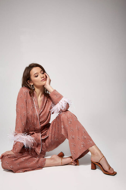 Pretty sexy woman beautiful face natural makeup brunette hair wear silk textile suit pants and blouse with feathers comfort casual home dress luxury lifestyle pajama party glamour fashion model. - Foto, immagini
