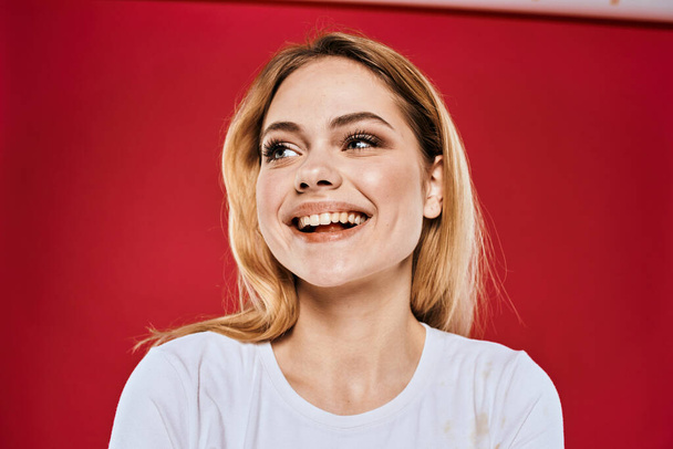 Χαρούμενη ξανθιά γυναίκα χειρονομίες με τα συναισθήματα χέρι lifestyle λευκό t-shirt κόκκινο απομονωμένο φόντο - Φωτογραφία, εικόνα