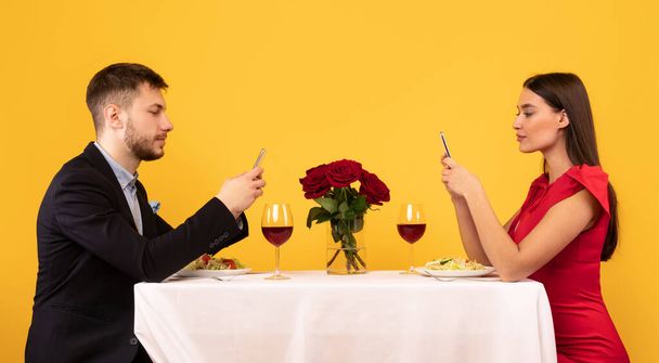 Ζευγάρι που χρησιμοποιούν κινητά τηλέφωνα σε ημερομηνία στο εστιατόριο, Studio Shot - Φωτογραφία, εικόνα
