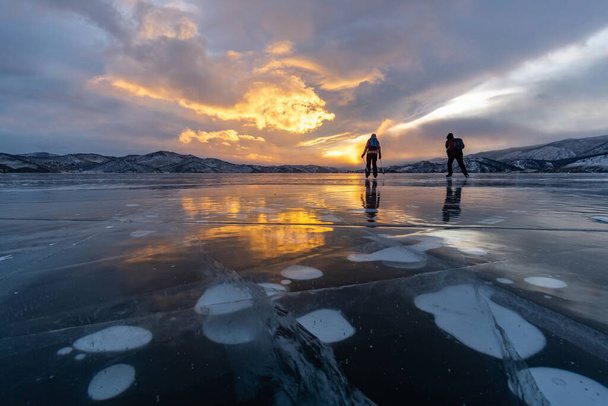 Two scaters rides on the ice of Lake Baikal at sunset - Photo, Image