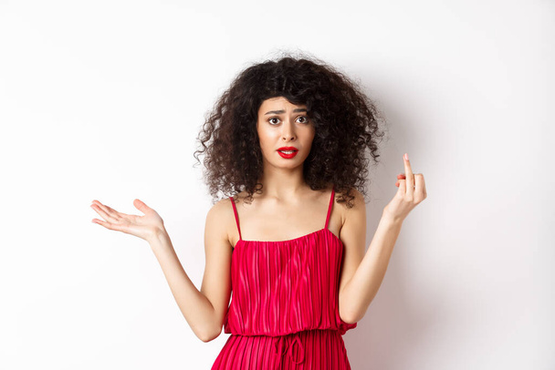 Annoyed caucasian woman in red dress, showing finger without wedding ring, arguing about marriage, standing pissed-off on white background - Foto, Imagem