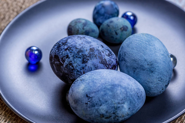Blue Easter eggs on a dark ceramic plate on burlap on an light wooden background.Spring religious holidays. - Fotografie, Obrázek