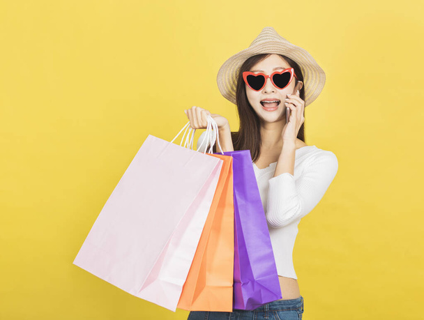 szczęśliwa młoda kobieta trzyma torby na zakupy i rozmawia przez telefon komórkowy - Zdjęcie, obraz