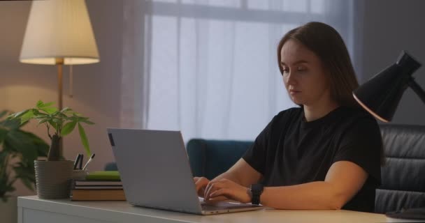 unavená žena pracuje večer s PC doma, cítí bolest hlavy, tření spánků pro zmírnění napětí a bolesti - Záběry, video
