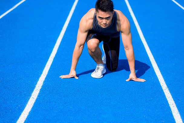 Asiático atleta masculino en pista de carreras está listo para correr - Foto, imagen
