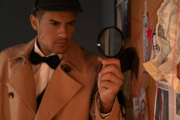 Old fashioned detective with magnifying glass near investigation board in office - Zdjęcie, obraz