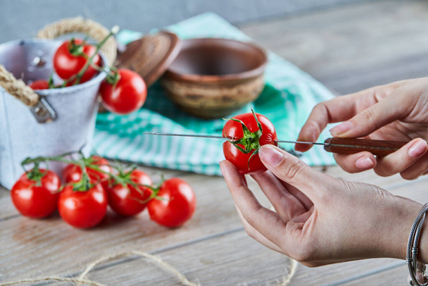 Woman hand cutting red tomato into two pieces with knife - Fotó, kép