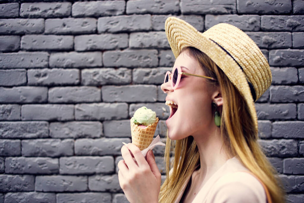 Красива жінка в елегантному стилі капелюх на відкритому повітрі морозиво цегляна стіна на фоні
 - Фото, зображення