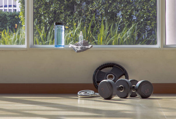 Dumbbells, water bottle and alcohol sanitizer spray on the gym or fitness studio. Equipment for doing sport exercises with free space. Exercise concept, Selective focus. - Foto, Imagem
