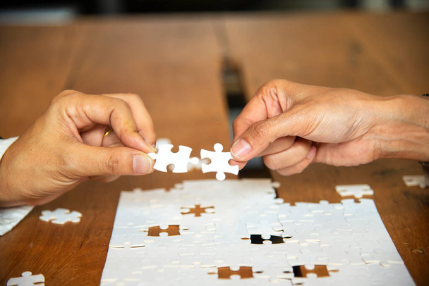 Hands of business people holding jigsaw, thinking about the successful good fit for concept of corporate recruitment, difference or cooperation strategy.Business Concept - Photo, Image