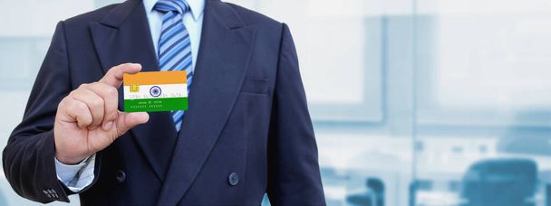 Imagen recortada del hombre de negocios con tarjeta de crédito de plástico con la bandera impresa de la India. Fondo borroso. - Foto, imagen
