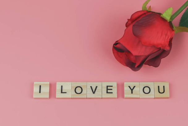 Top view or flat lay of wooden letters I LOVE YOU on pink background with red  rose. Valentine's day and love concept. - Photo, Image