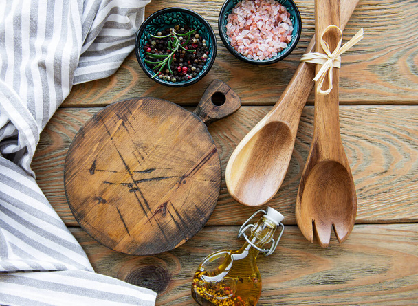 Stare zabytkowe naczynia kuchenne. Drewniane łyżki, deska do krojenia, serwetka i przyprawy na starym drewnianym stole. Widok z góry - Zdjęcie, obraz