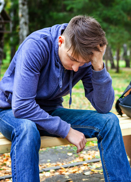 Sad Young Man sit on the Bench in the Autumn Park - Foto, Imagen