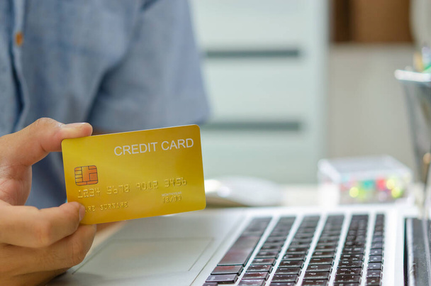 Mann Hand hält eine Kreditkarte für Online-Transaktionen oder Online-Shopping. Beantragen Sie eine Kreditkarte, machen Sie ein finanzielles Darlehen - Foto, Bild