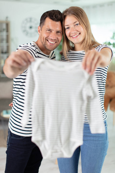 parents with baby clothes dreamingly and smiling - Фото, зображення
