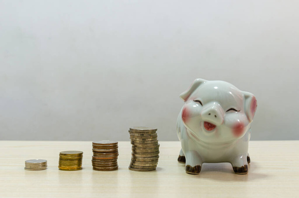 White pig piggy bank and coins money on wood table.Concept of finance and saving money, investment or retirement age in the future. - Photo, Image