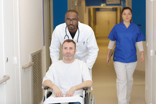 doctor pushing male patient in wheelchair - Fotoğraf, Görsel